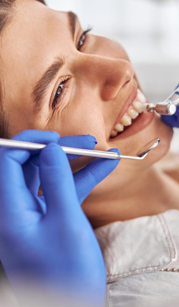 Female patient at dental procedure, doctor using dental instruments in modern dental clinic
